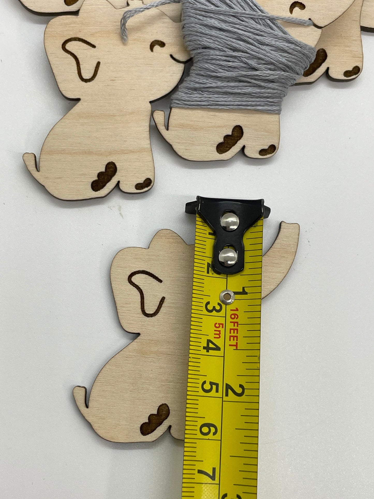 Wooden elephant cutouts with a measuring tape for scale on a white background