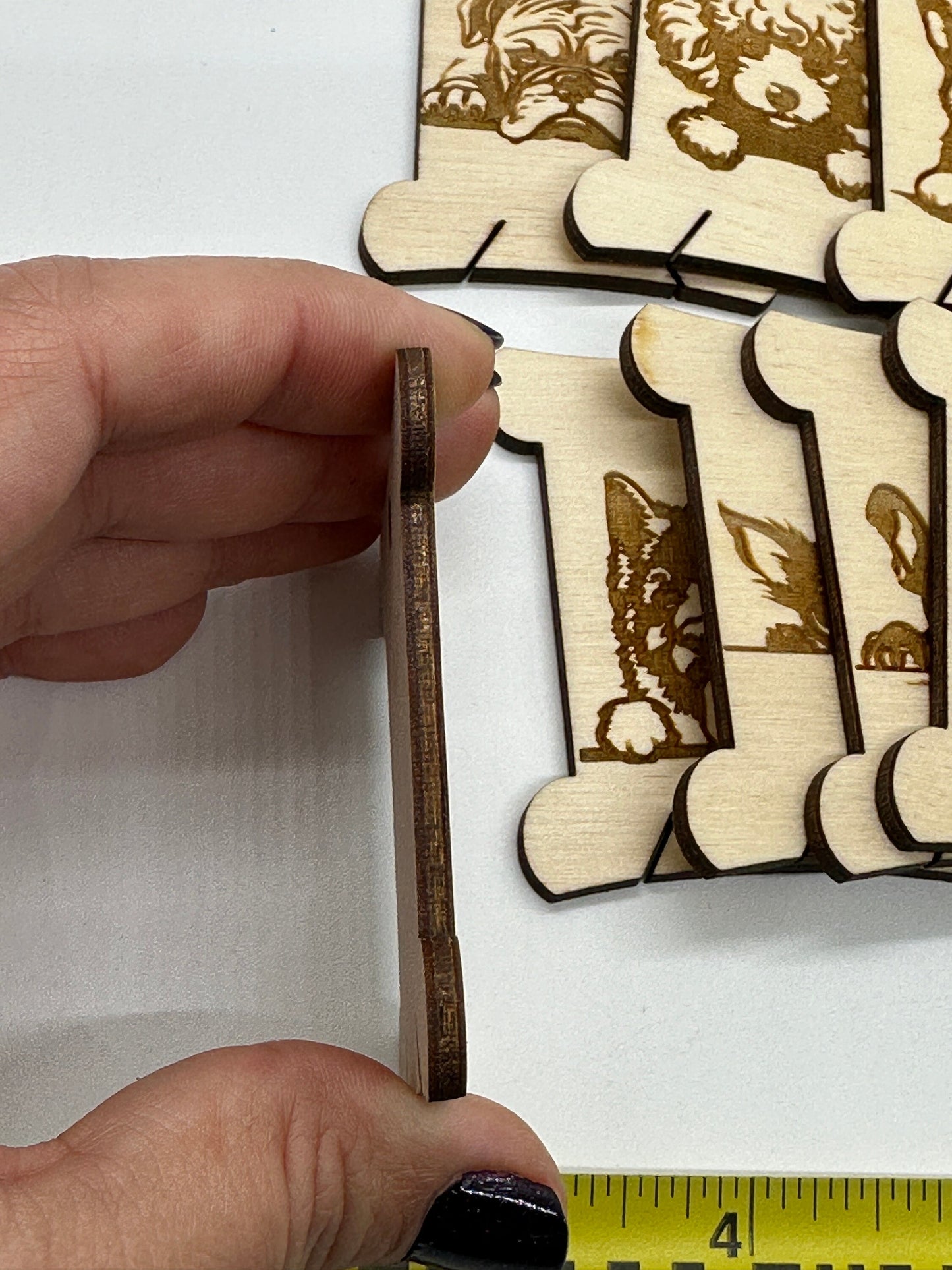 Wooden bobbin with dog designs held by a hand with a ruler for scale.