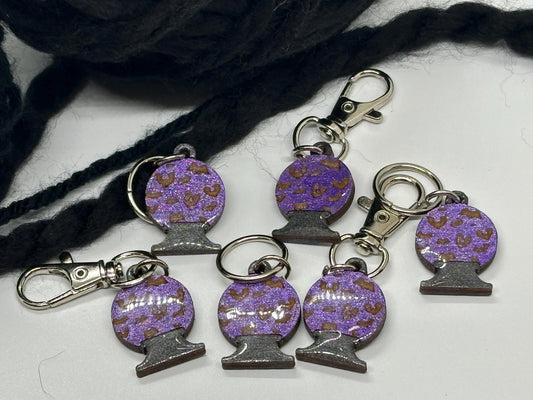 Purple and brown decorative keychains with metal clasps on a white surface.