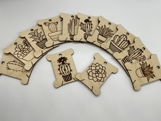 Wooden tags with cactus designs arranged in a semi-circle on a white background