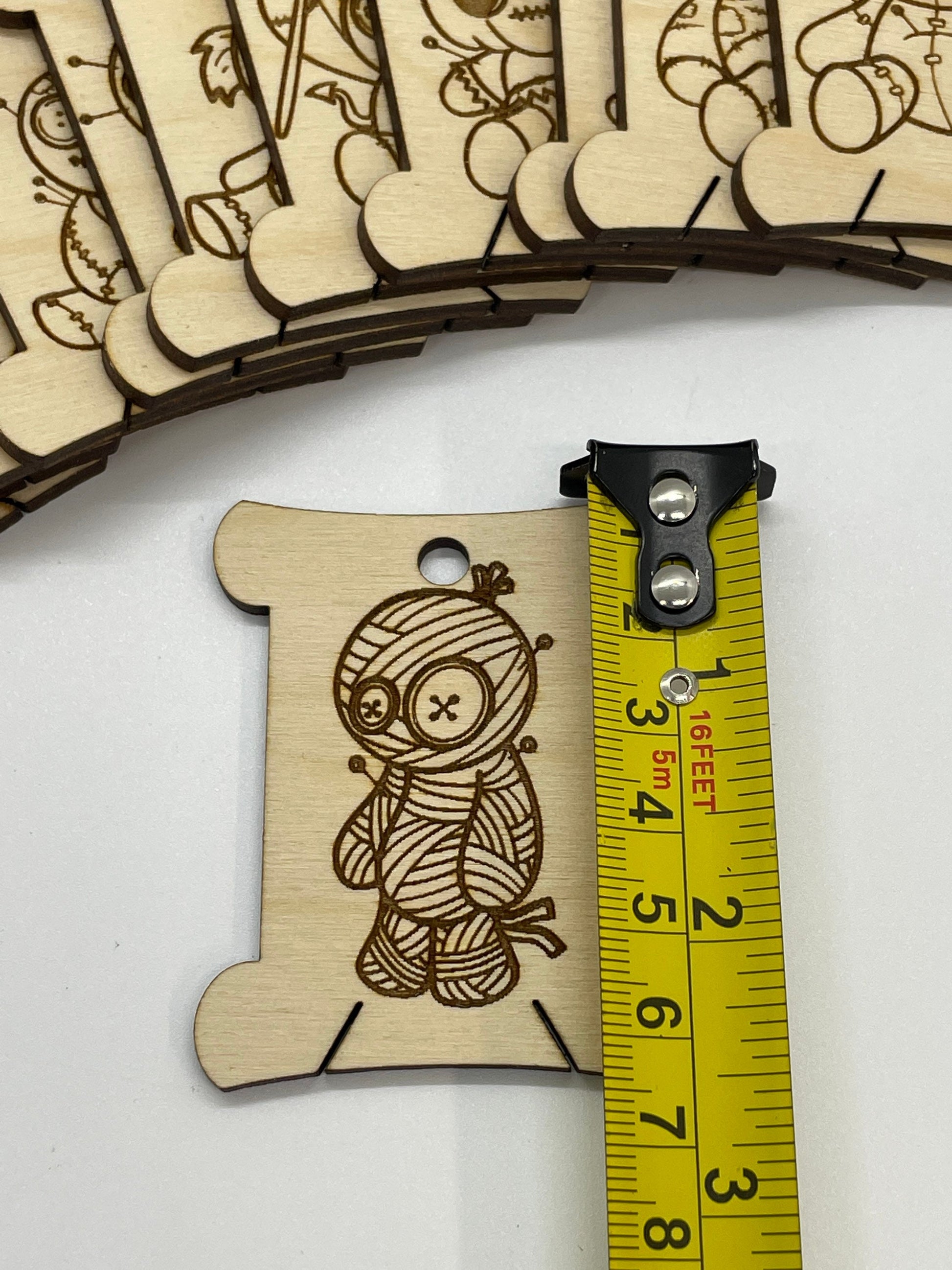 Wooden mummy-shaped cutout with laser engraving, next to a measuring tape for scale.