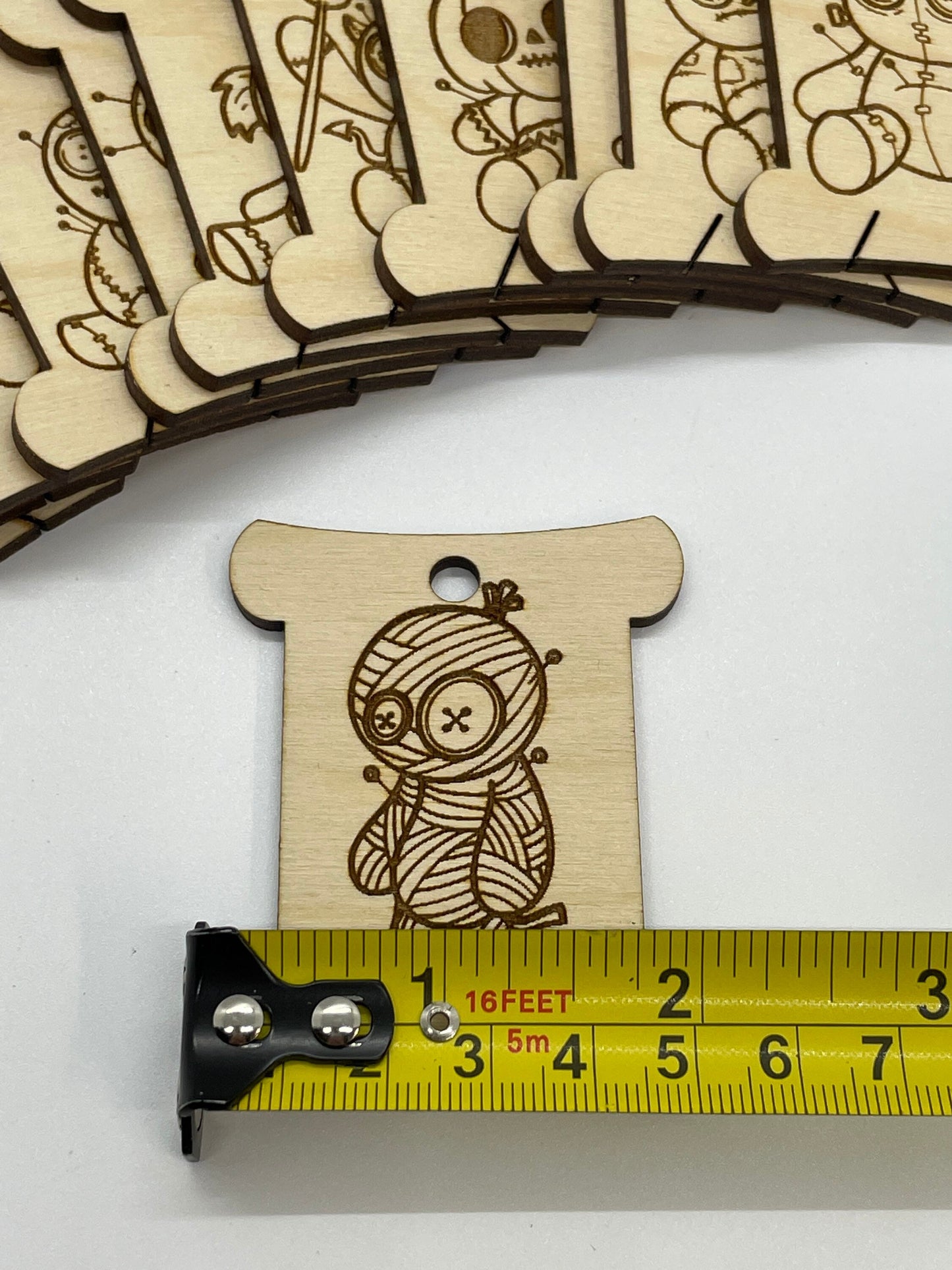 Wooden mummy design next to a measuring tape on a white background