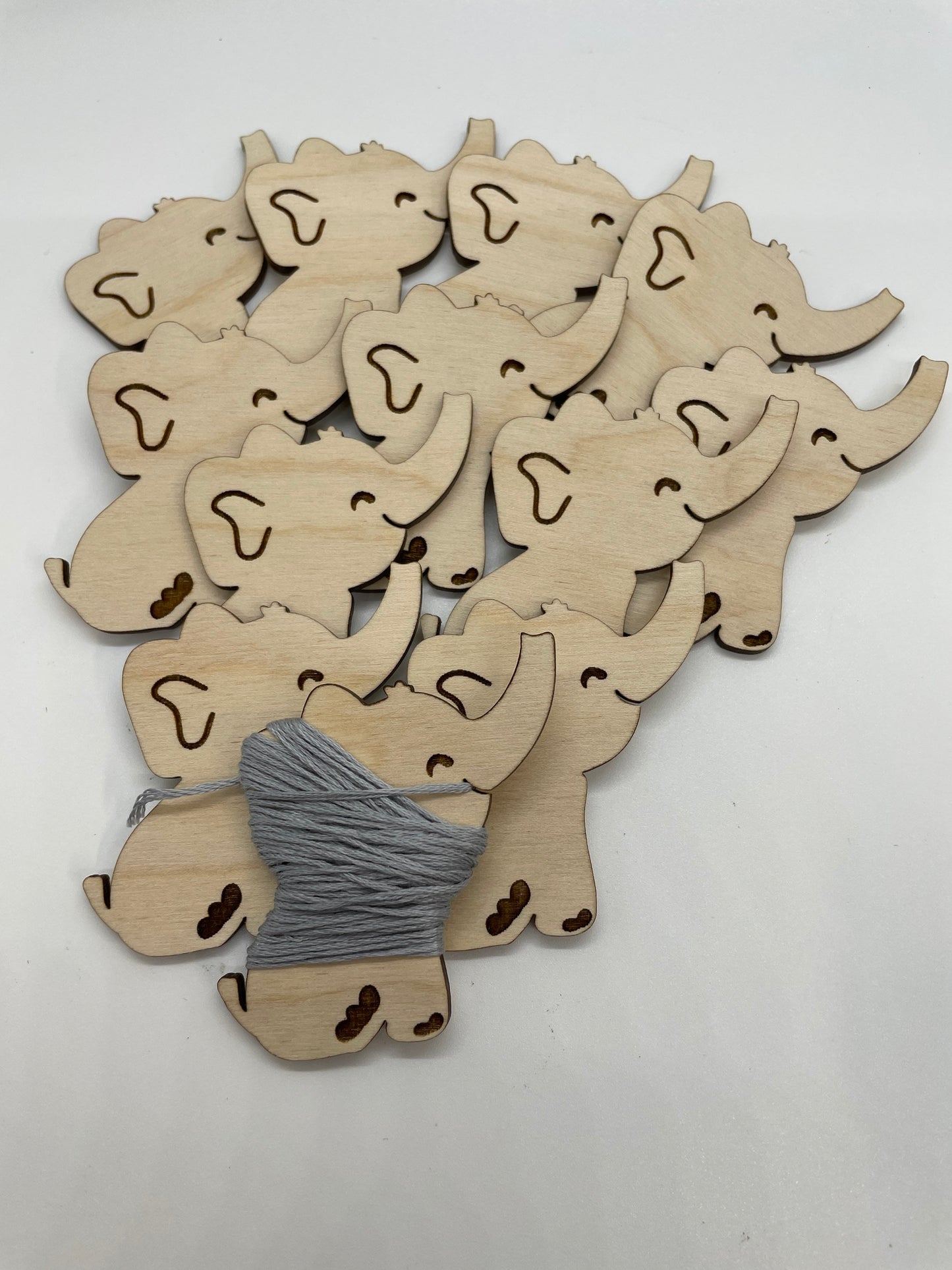 Wooden elephant cutouts with a ball of yarn on a white background