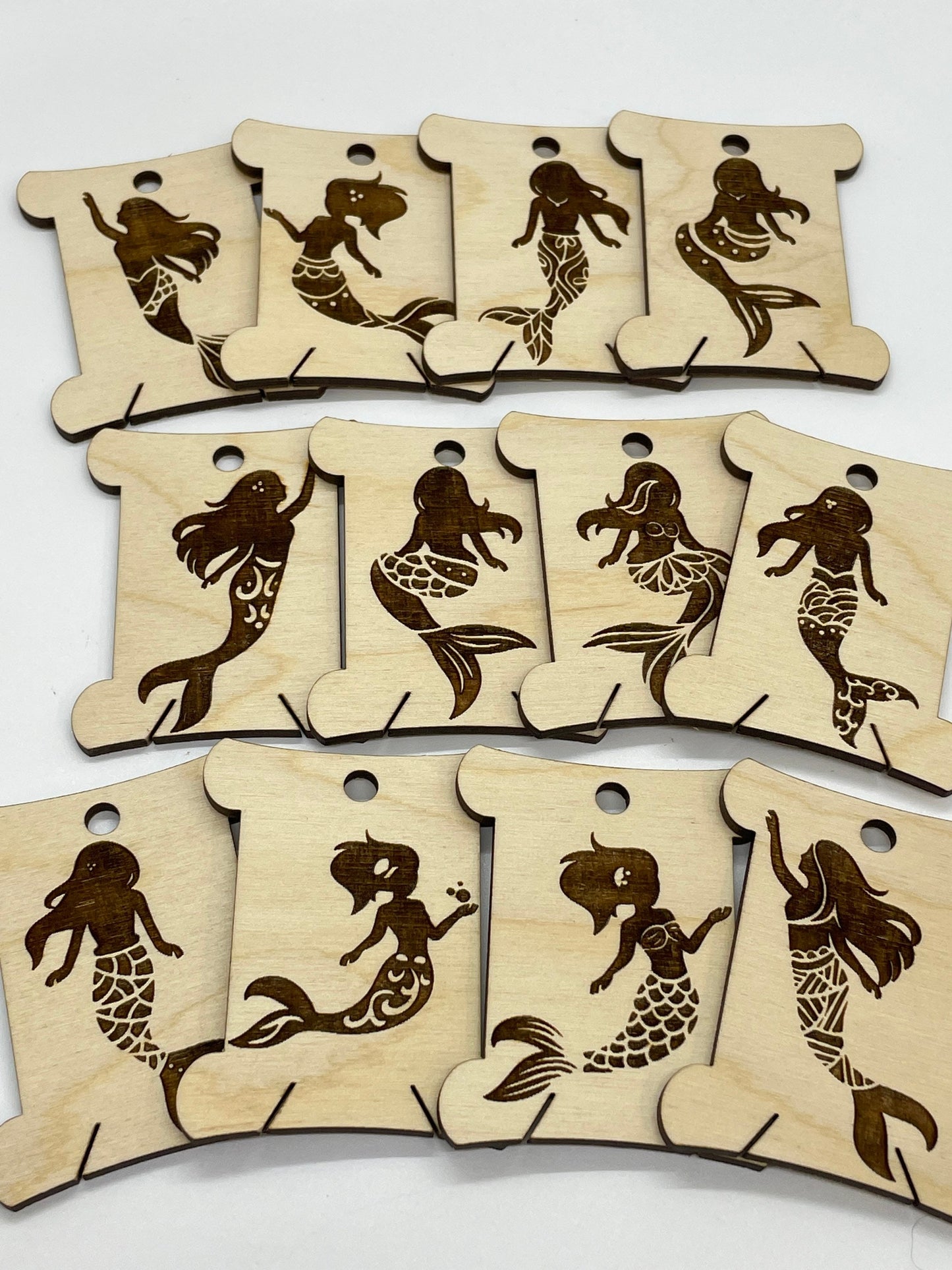 Set of wooden bobbins with mermaid designs on a white background