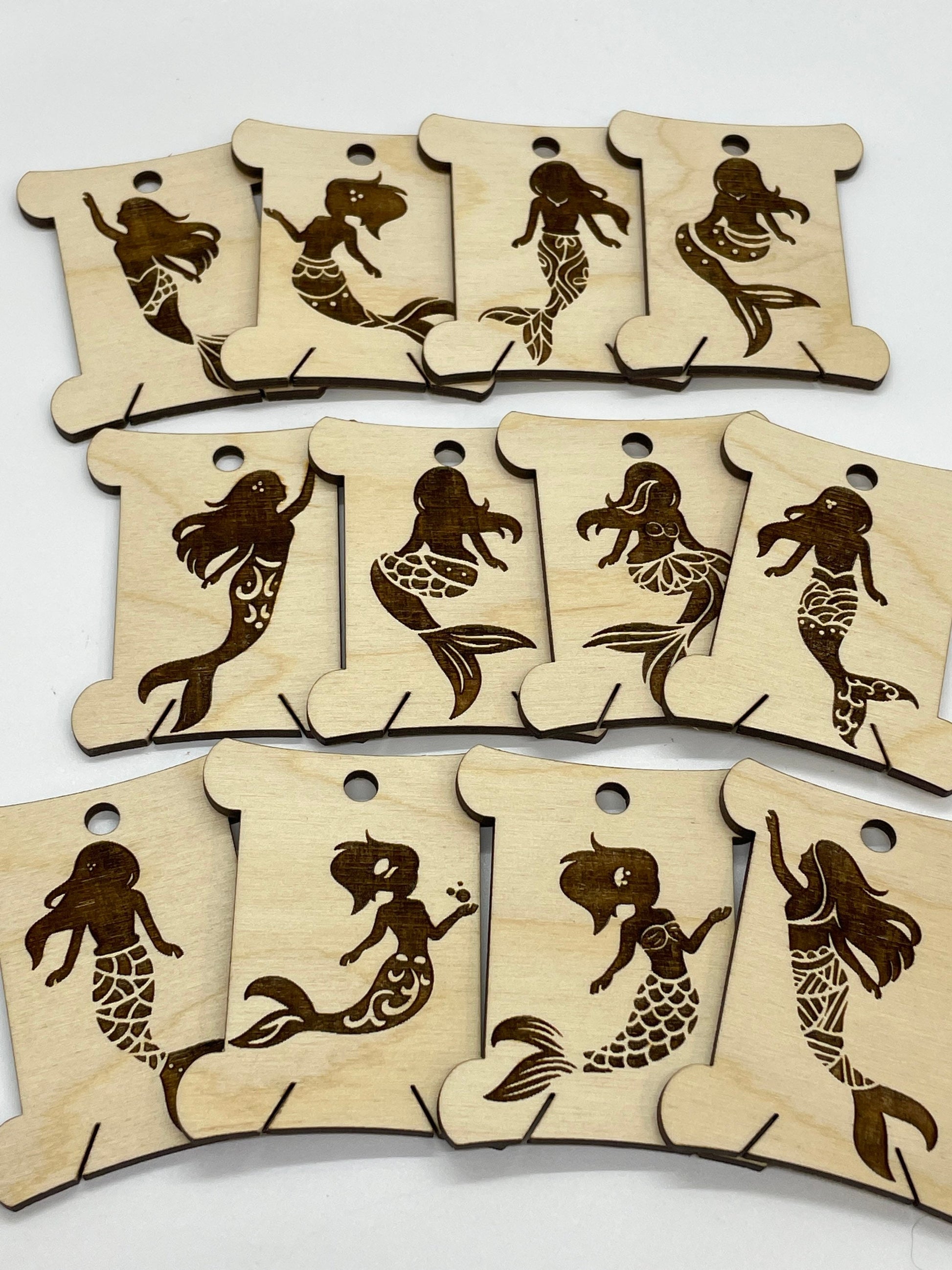 Set of wooden bobbins with mermaid designs on a white background
