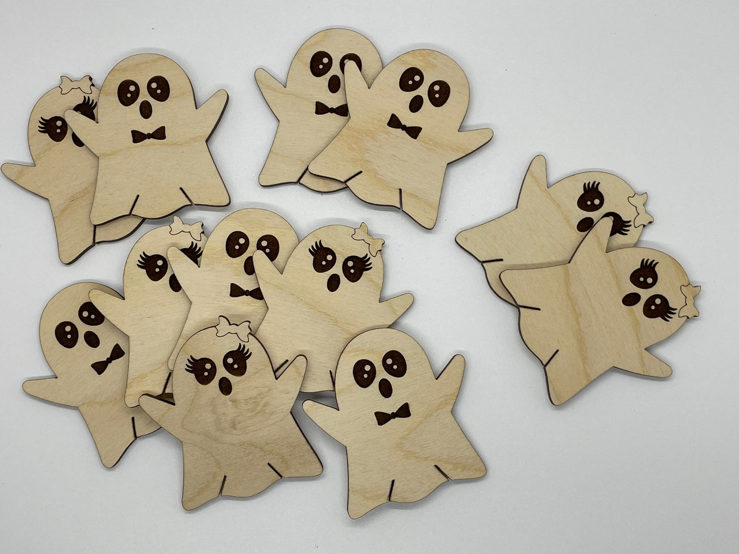 Wooden ghost cutouts with facial expressions on a white background