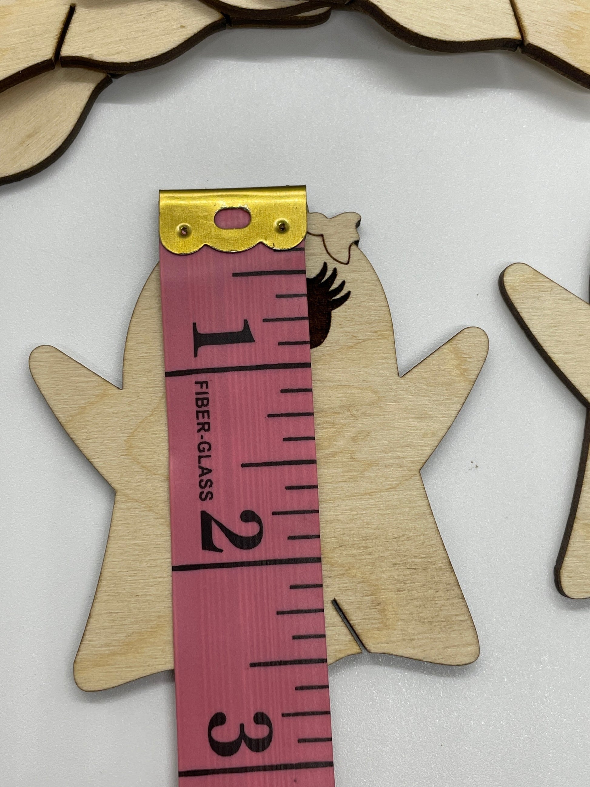 Wooden cutout of a hand with a pink measuring tape showing 2.5 inches