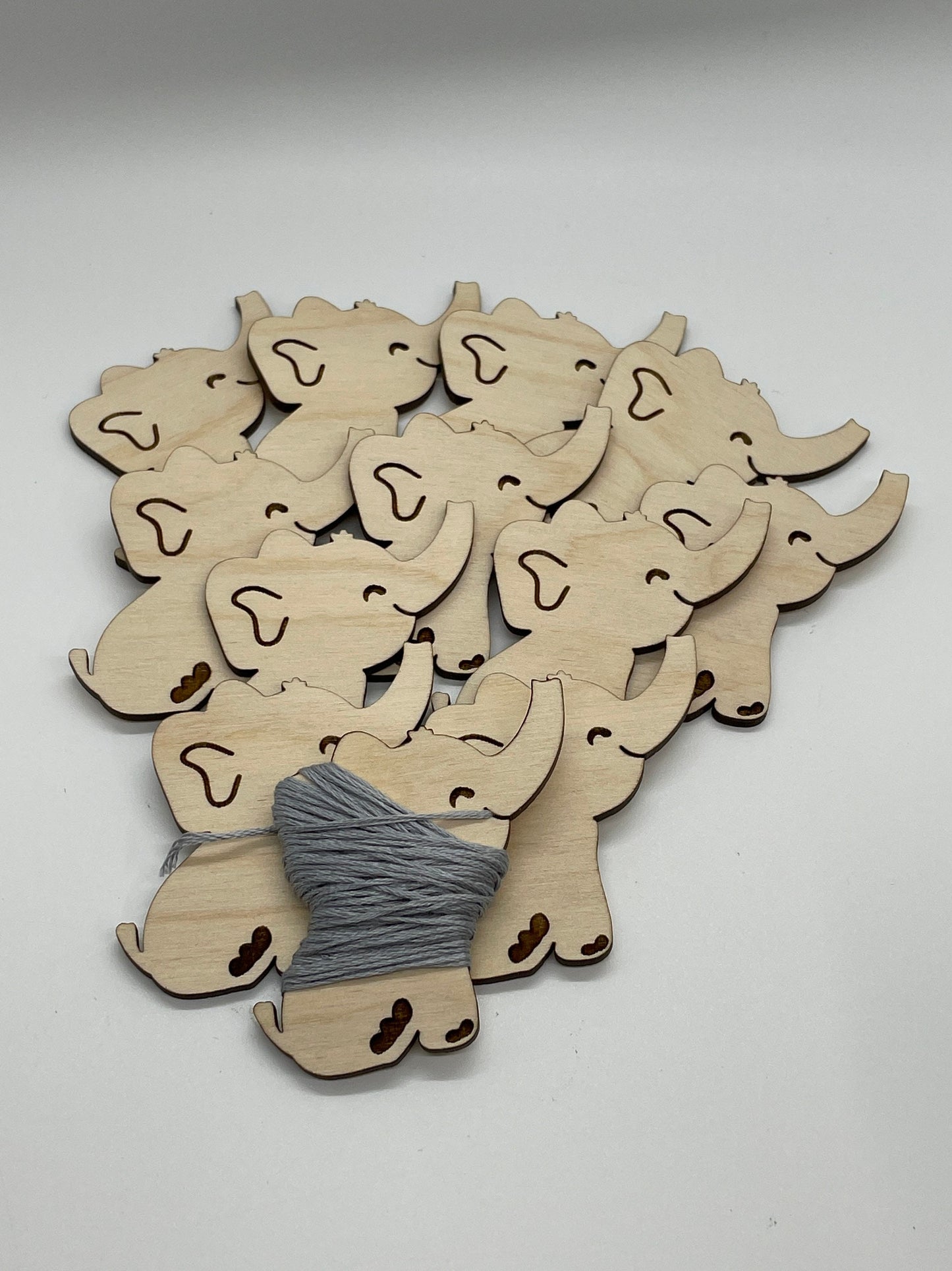 Wooden elephant shapes with a spool of thread on a white background