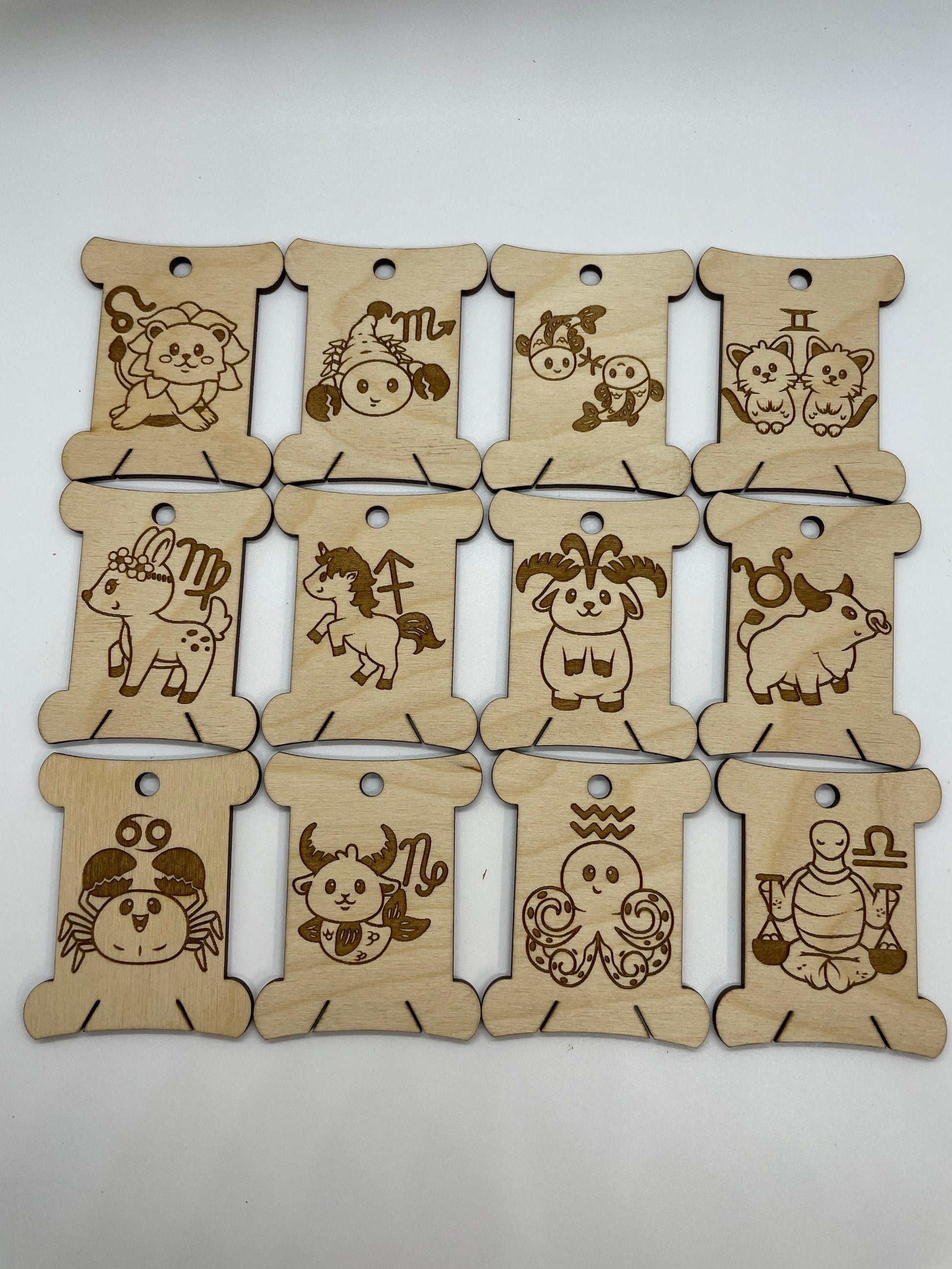 Set of twelve wooden zodiac bobbins on a white background