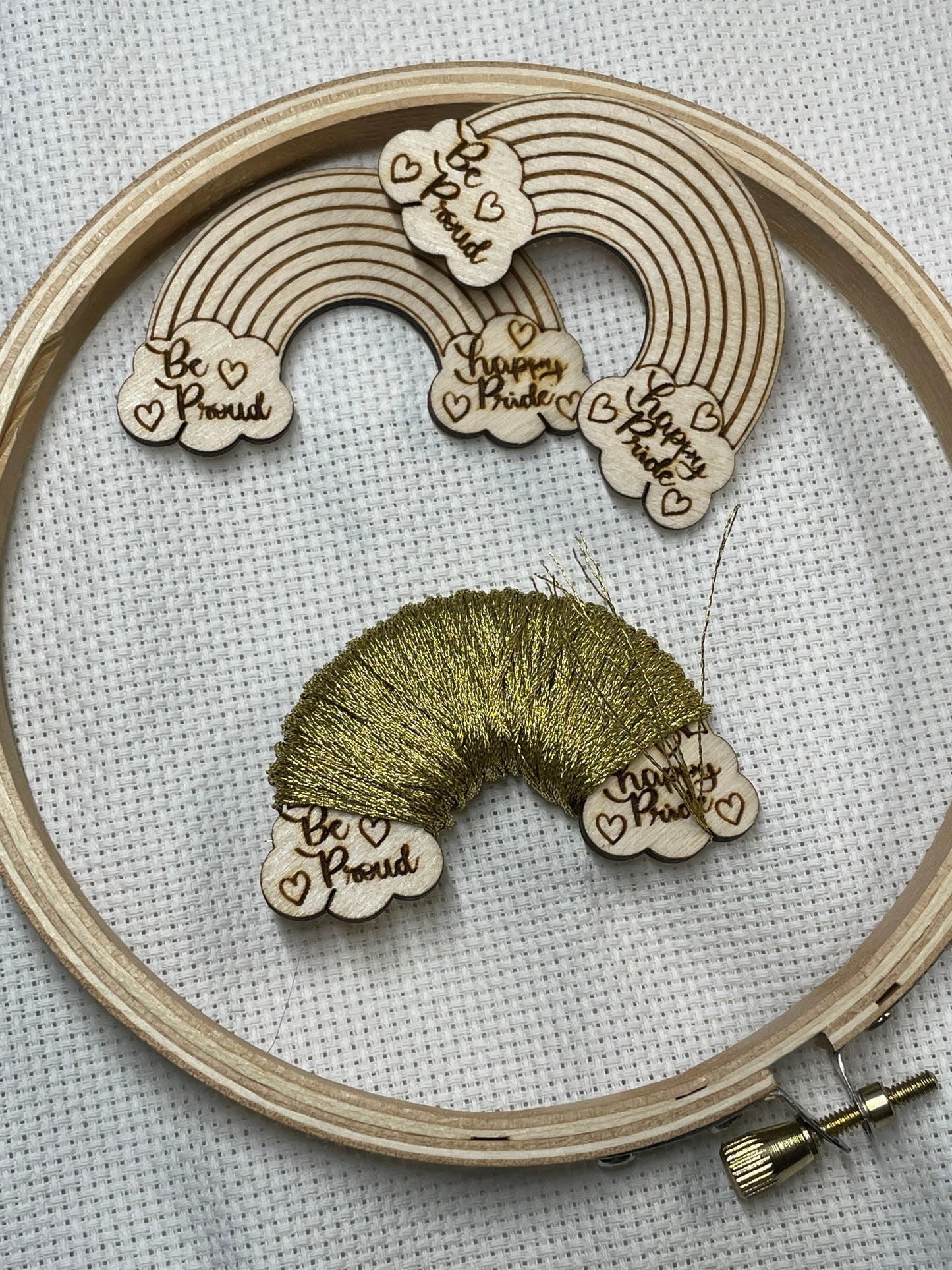Embroidery hoop with wooden rainbow and heart-shaped bobbins on a light background