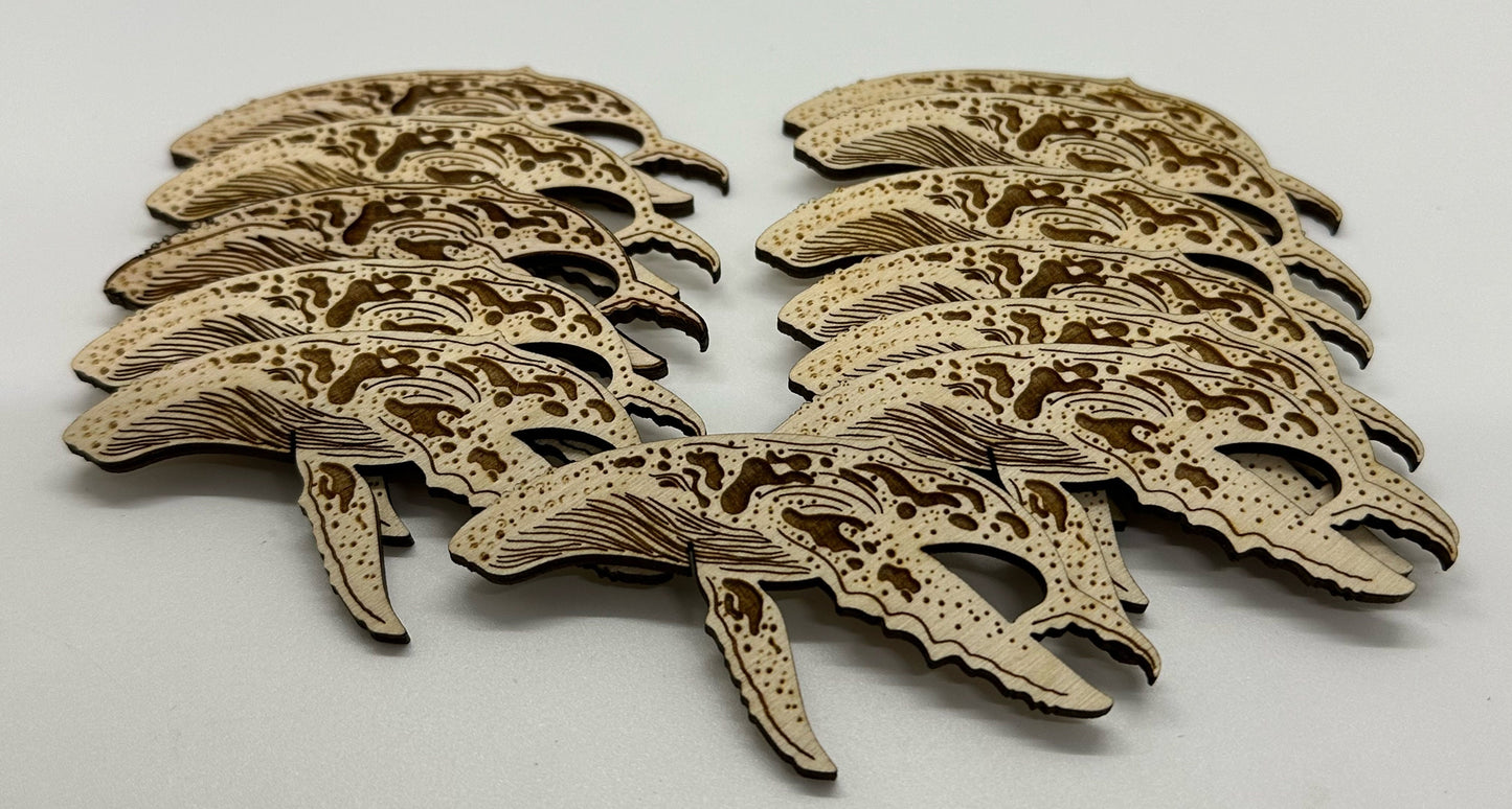 Set of laser-cut wooden humpback whale shapes on a white background