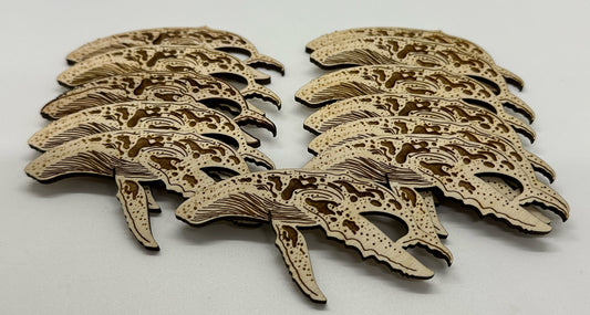 Set of laser-cut wooden humpback whale shapes on a white background