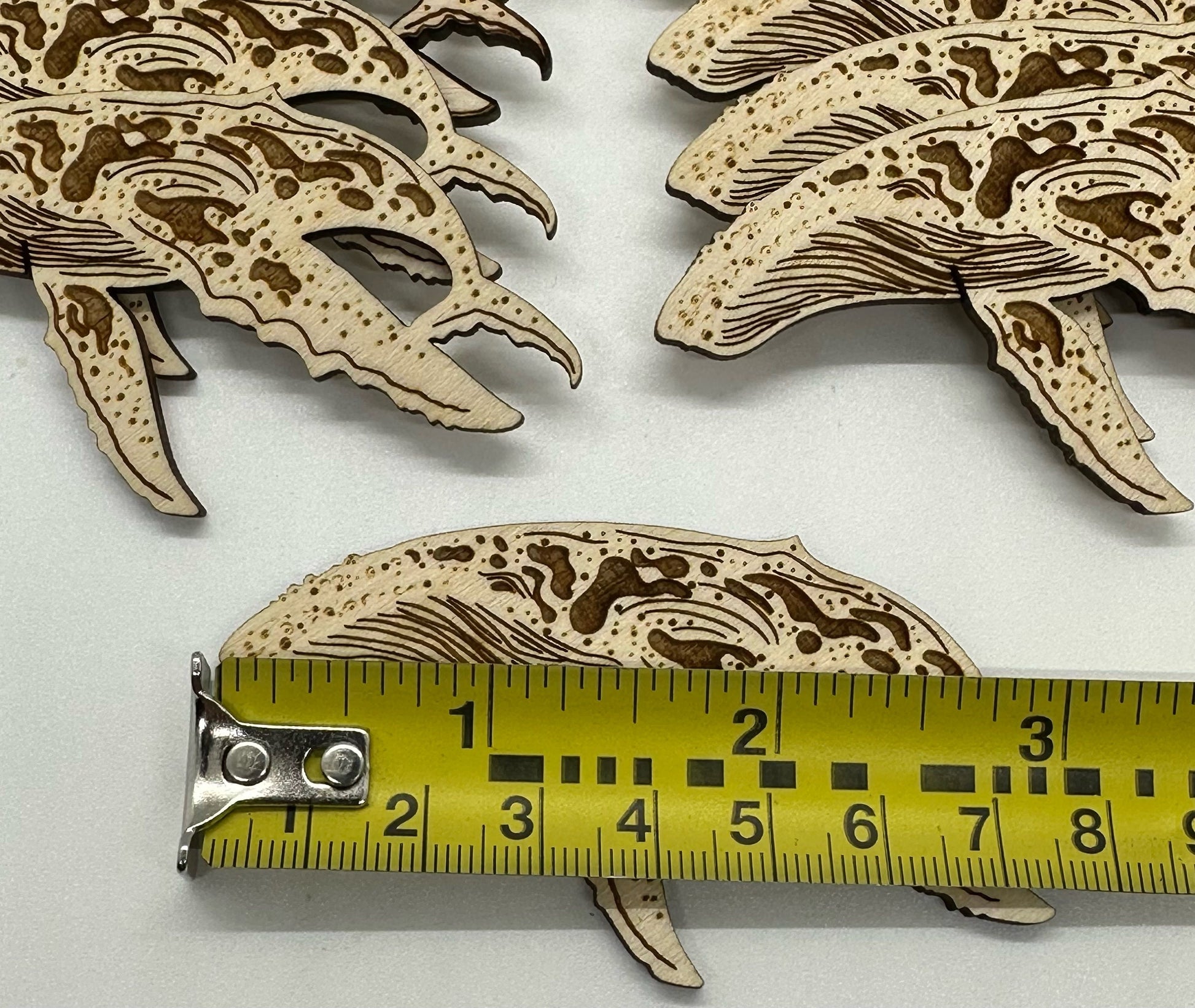 Wooden humpback whale cutouts on a white background with a ruler