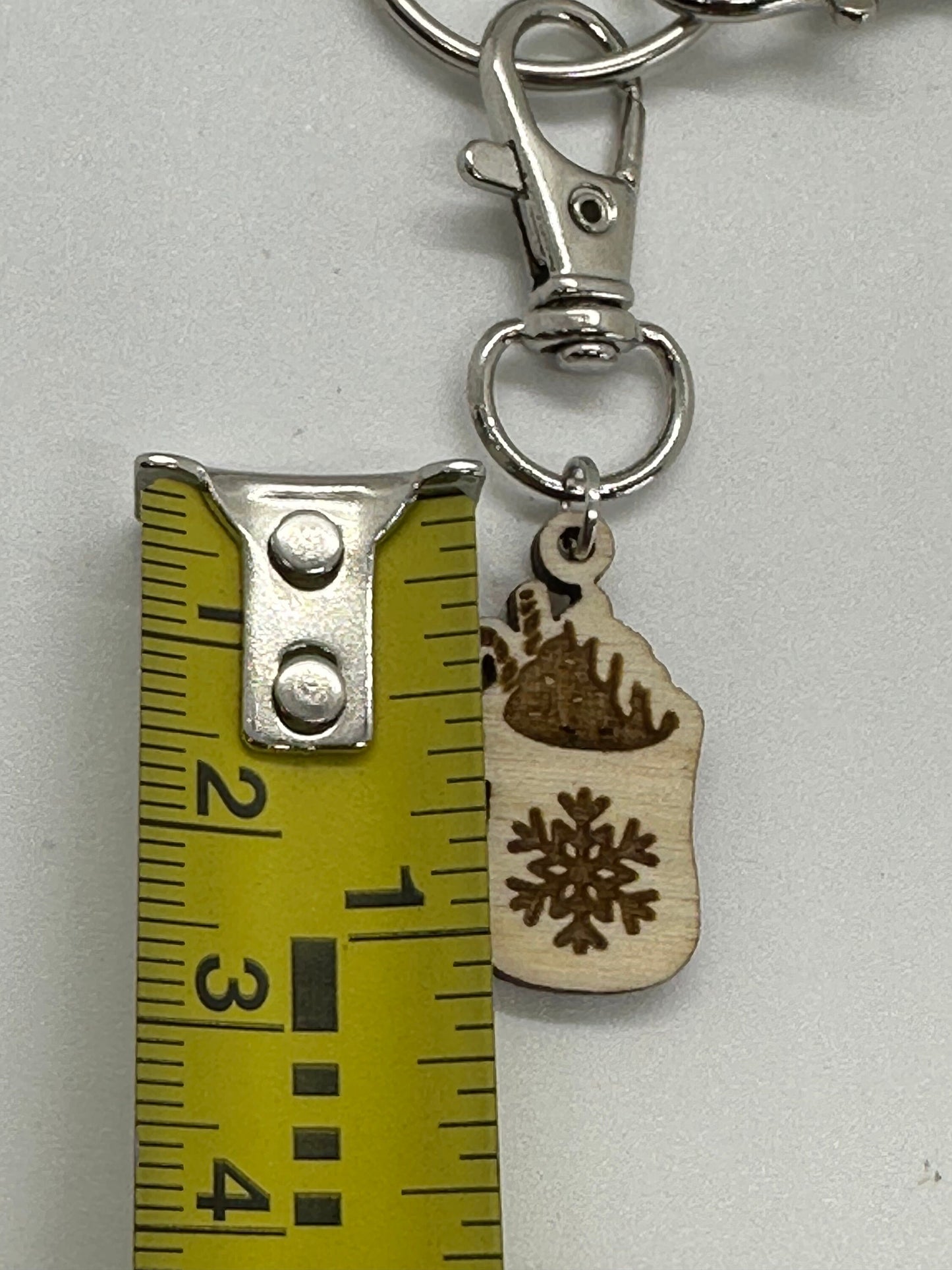 Keychain with wooden mug-shaped charm and snowflake design, next to a ruler for scale.