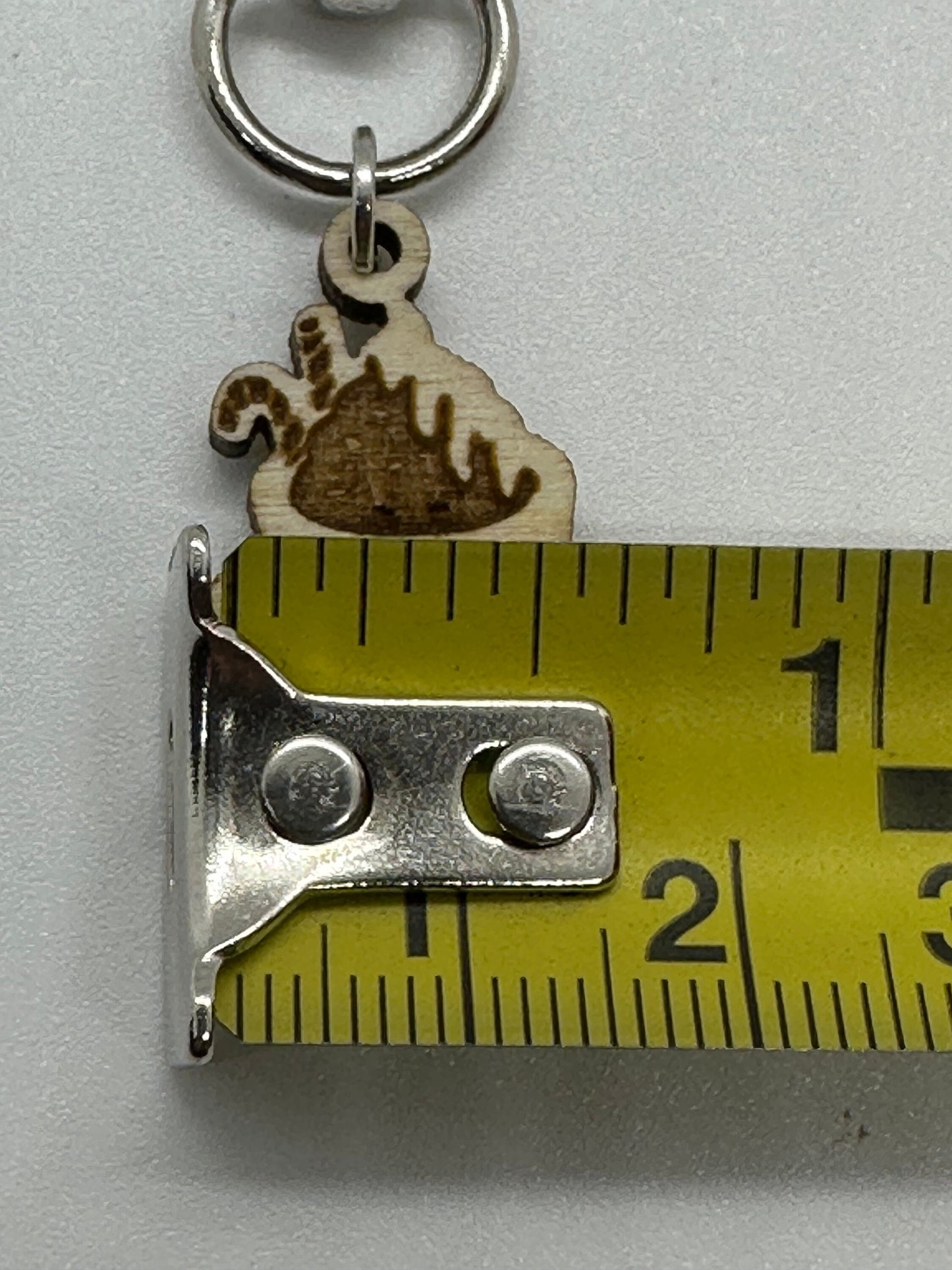 Keychain with wooden mug print design on a metal clip, measured against a tape measure.
