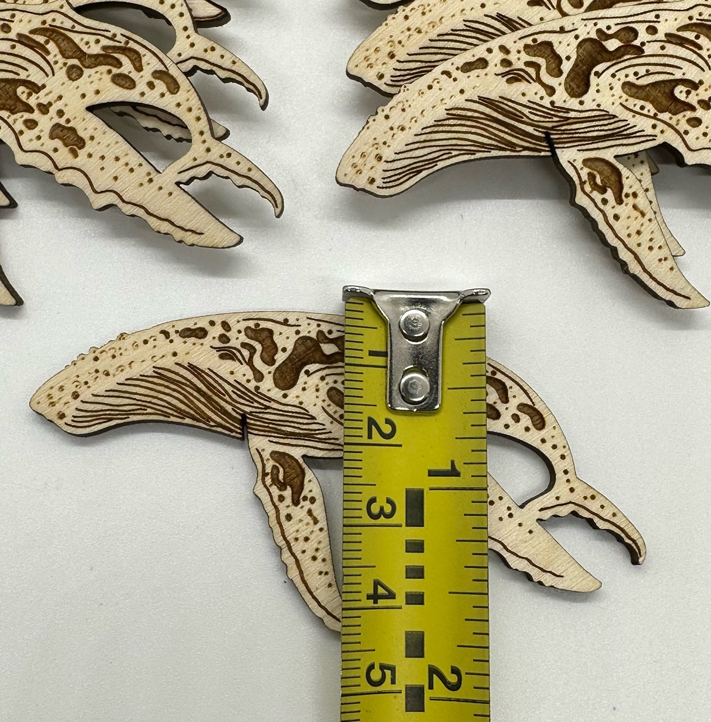 Wooden humpback whale cutouts on a white background with a ruler