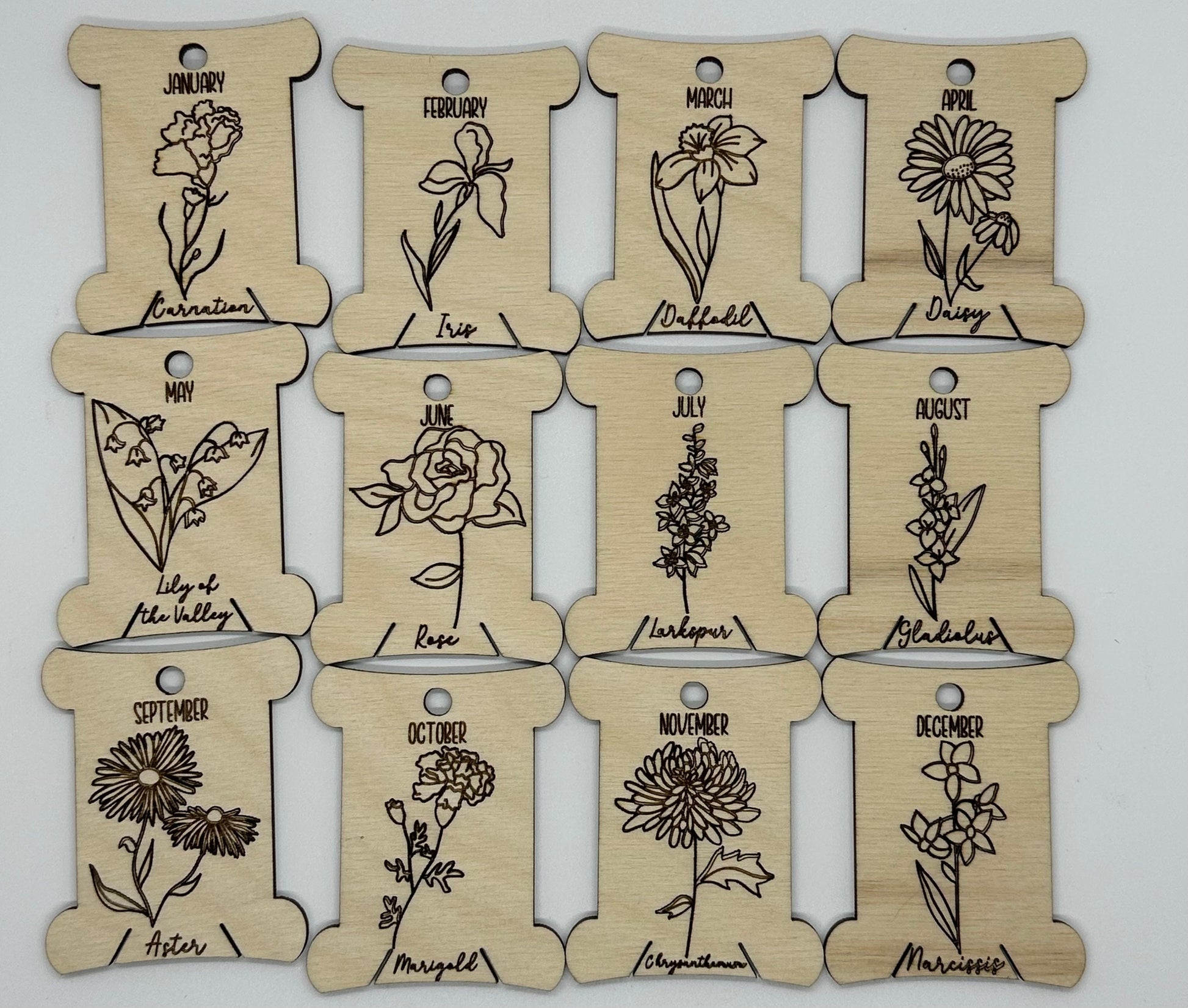 Wooden bobbins with floral illustrations and months' names on a white background