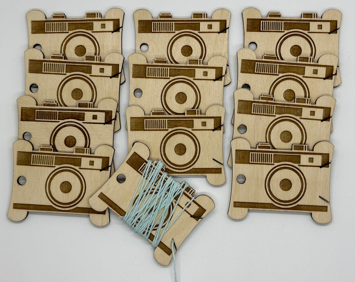 Wooden camera-shaped bobbins with a string on a light gray background