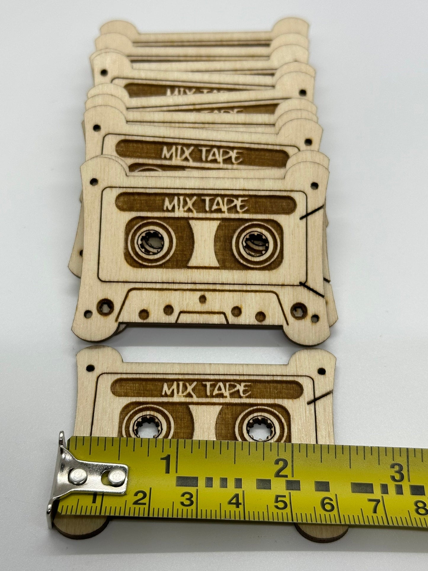 Wooden mix tape bobbins with a measuring tape for scale on a white background