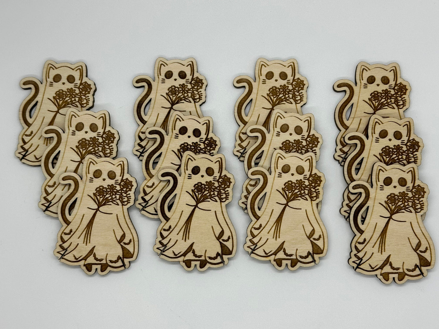Wooden cat-shaped bobbins with floral bouquets on a white background