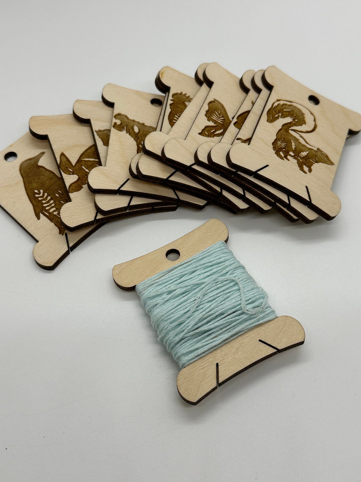 Wooden thread spools with animal designs on a white background