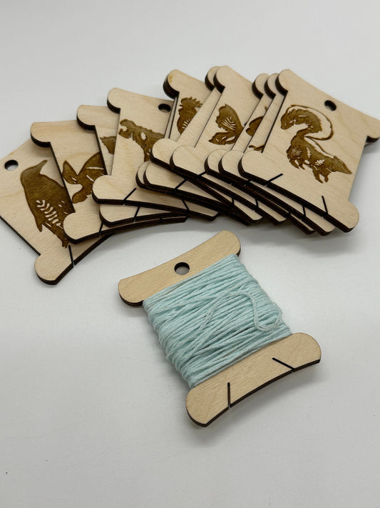 Wooden thread spools with animal designs on a white background