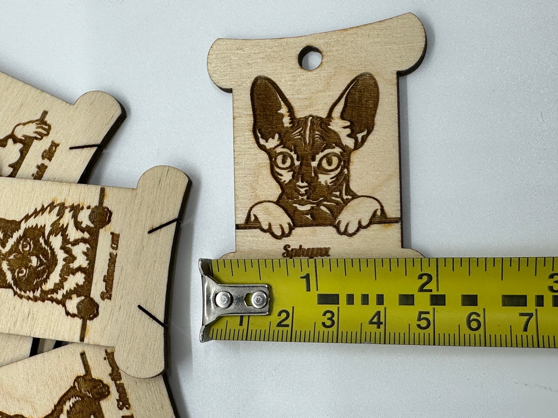 Wooden tags with engraved cat illustrations on a white background