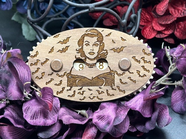 Wooden counter with engraved design of a woman and numbers, surrounded by purple flowers.