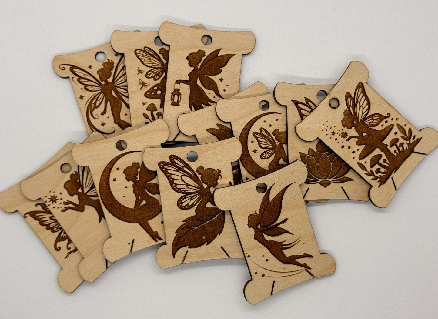 Wooden tags with engraved fairy and butterfly designs on a white background
