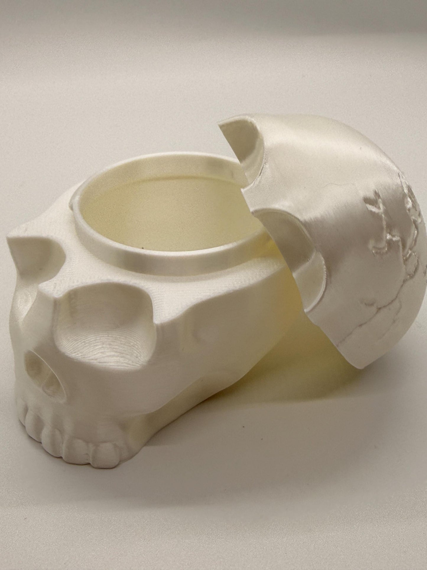 White ceramic skull-shaped container on a light gray background